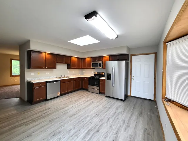 a large kitchen with a large counter top stainless steel appliances and wooden floor