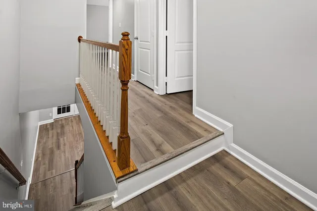 a view of a hallway with wooden floor and a bathroom