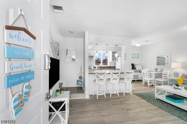 a living room with stainless steel appliances furniture a rug and a kitchen view