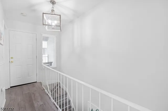 a view of a hallway with wooden floor and chandelier