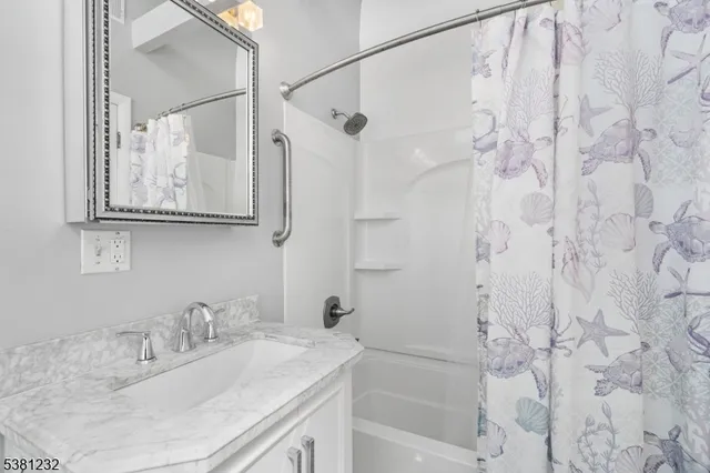 a bathroom with a granite countertop sink a mirror a shower and a bathtub