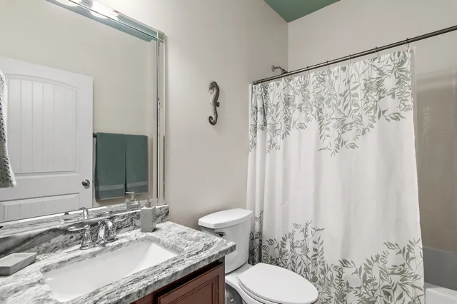 a bathroom with a granite countertop sink toilet and a mirror