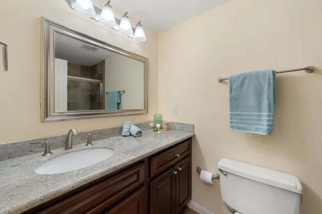 a bathroom with a granite countertop toilet sink and mirror
