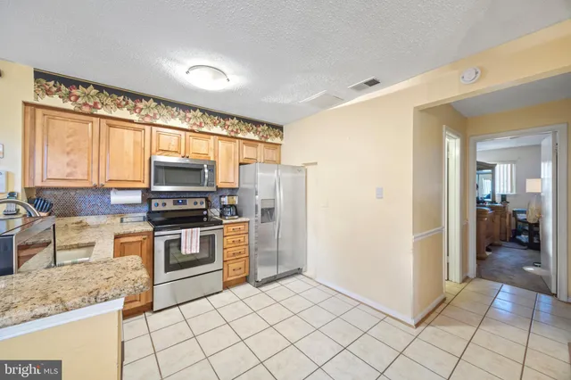 a kitchen with stainless steel appliances granite countertop a refrigerator and a stove top oven