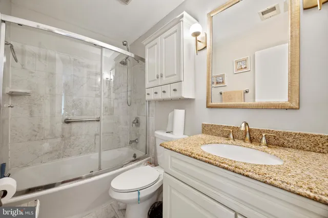 a bathroom with a granite countertop sink a toilet and shower