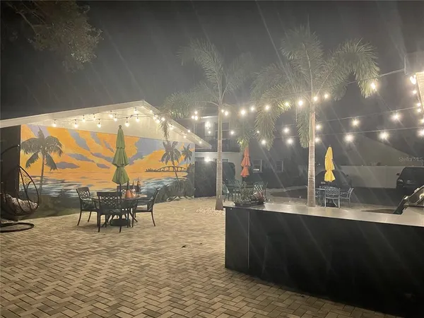 a view of a backyard with table and chairs potted plants and a large tree