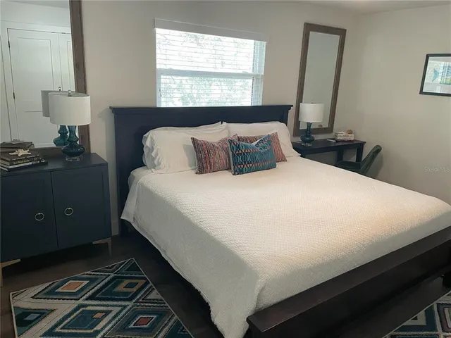 a bedroom with a bed and a mirror next to a window