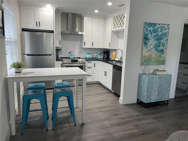 a kitchen with stainless steel appliances granite countertop a table chairs sink refrigerator and cabinets