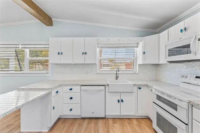 a kitchen with granite countertop a stove a sink and white cabinets with wooden floor