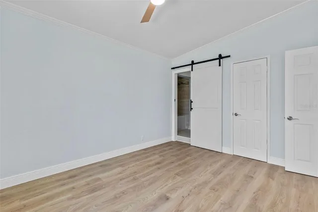 a view of empty room with wooden floor and fan