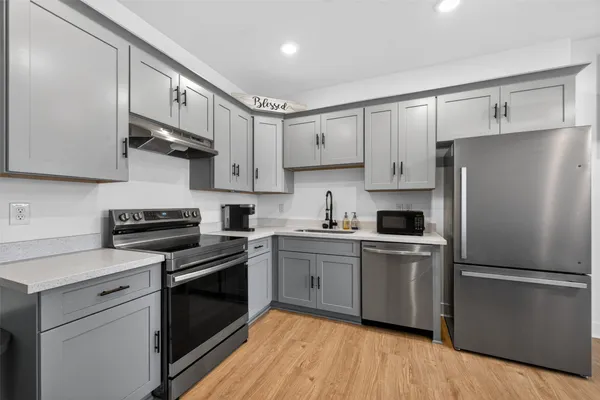 a kitchen with cabinets stainless steel appliances and wooden floor