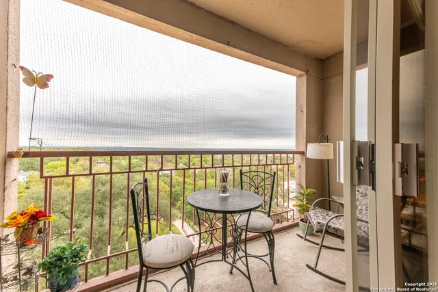 a balcony with chairs and a potted plant