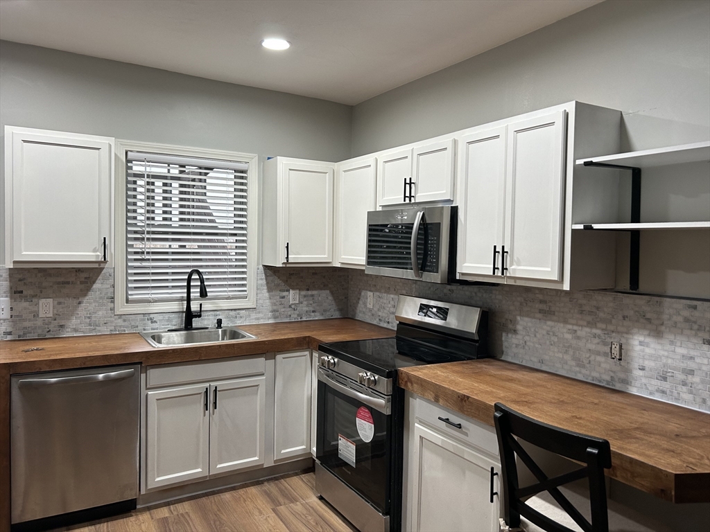 131 Stewart Street, Unit 2 Fall River, MA 02720 - Photo 2 of 16 a kitchen with stainless steel appliances granite countertop a sink a stove a microwave a counter space and cabinets