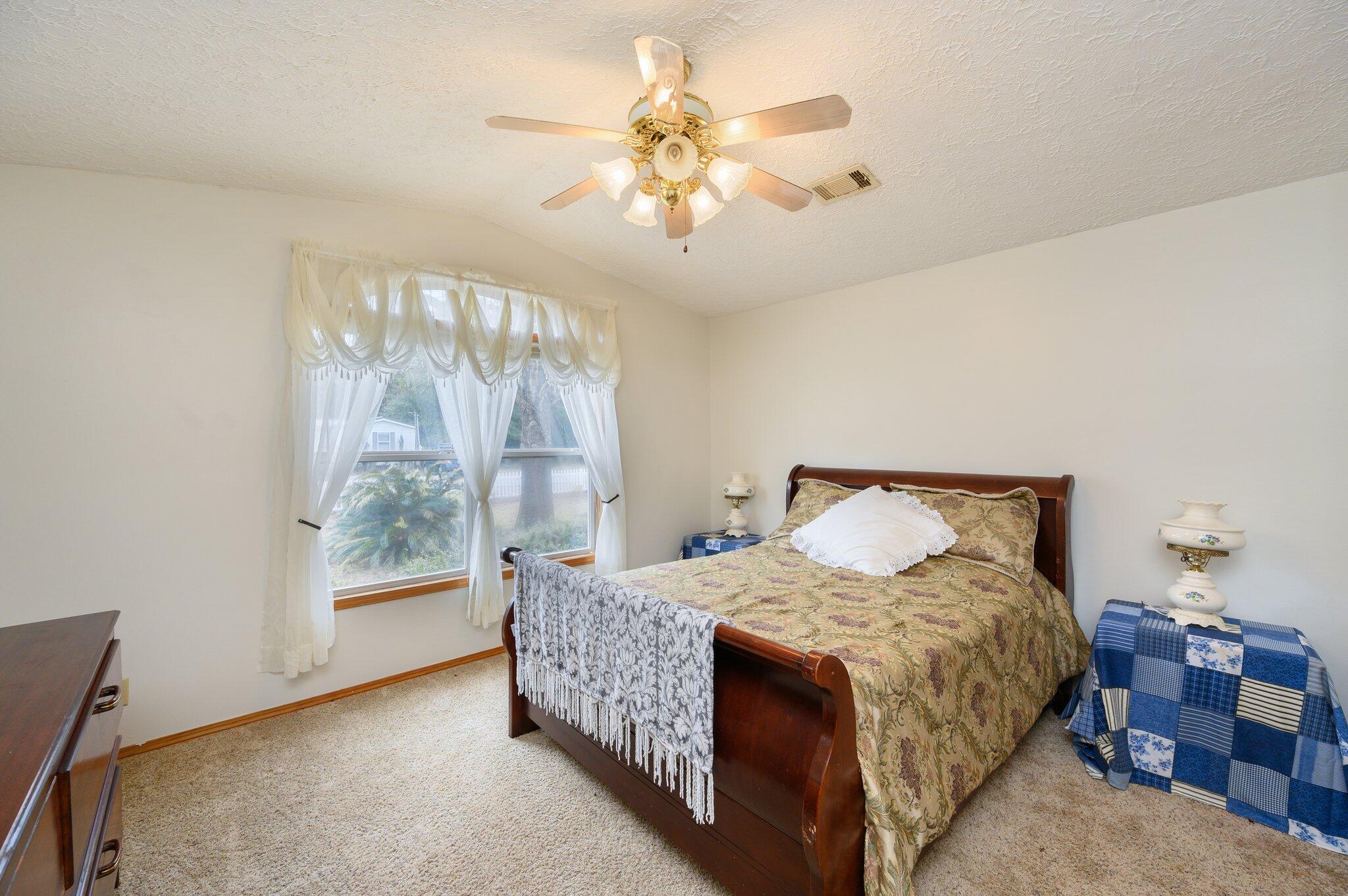 52 Tulip Avenue DeFuniak Springs, FL 32433 - Photo 6 of 34 a bedroom with a large bed and a chandelier fan