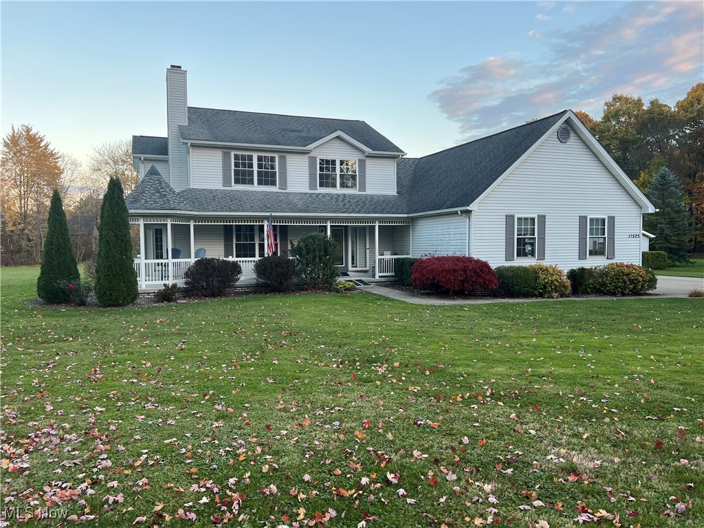 View of front of house featuring a porch, a front lawn, a chimney, and roof with shingles