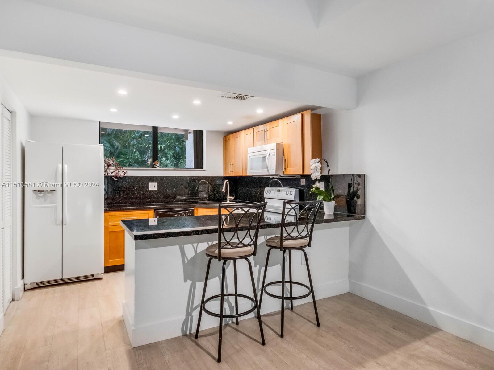 2430 Brickell Avenue, Unit 105A Miami, FL 33129 - Photo 6 of 27 a kitchen with stainless steel appliances kitchen island granite countertop a stove a sink and a refrigerator