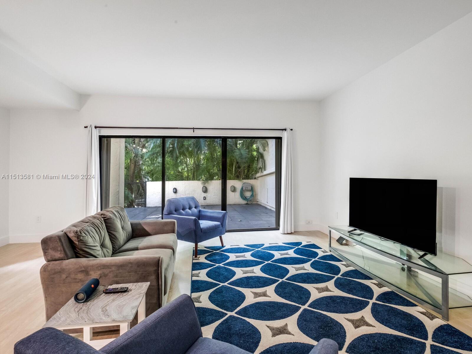 2430 Brickell Avenue, Unit 105A Miami, FL 33129 - Photo 7 of 27 a living room with a flat screen tv and a floor to ceiling window