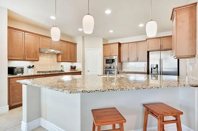 a kitchen with stainless steel appliances granite countertop a sink a stove and a refrigerator