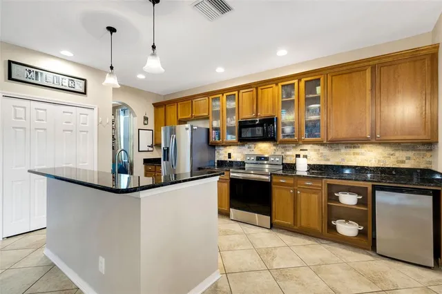 a kitchen with stainless steel appliances granite countertop a refrigerator a stove top oven and a sink with granite countertops