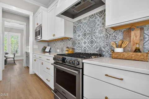 a kitchen with granite countertop a stove and a white cabinets