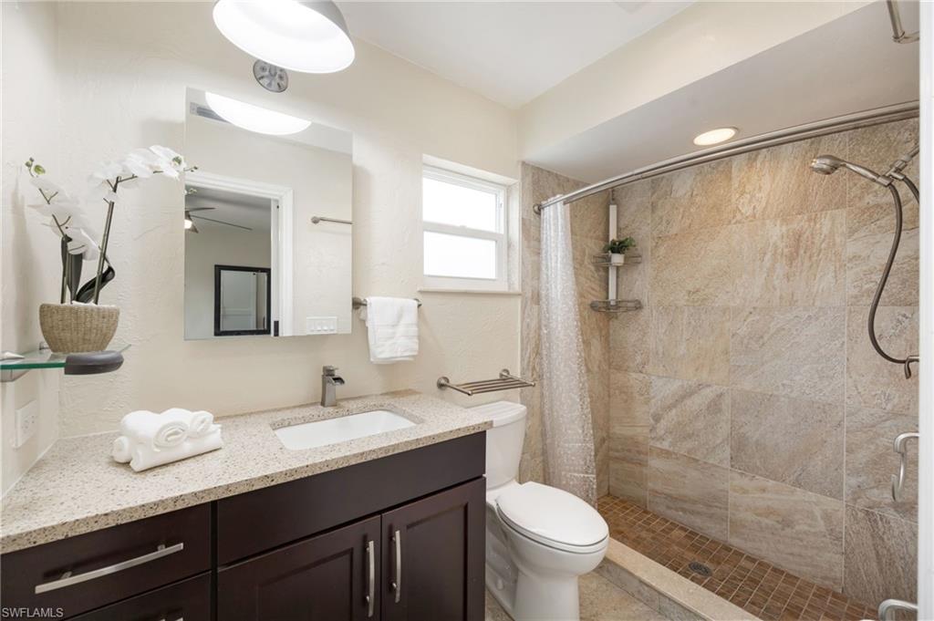 1324 Monarch Circle Naples, FL 34116 - Photo 11 of 23 a bathroom with a granite countertop sink toilet a mirror and shower