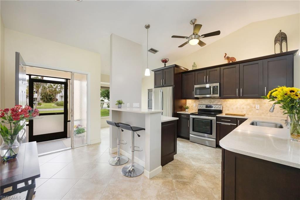 1324 Monarch Circle Naples, FL 34116 - Photo 2 of 23 a kitchen with stainless steel appliances kitchen island granite countertop a table chairs in it and wooden floors