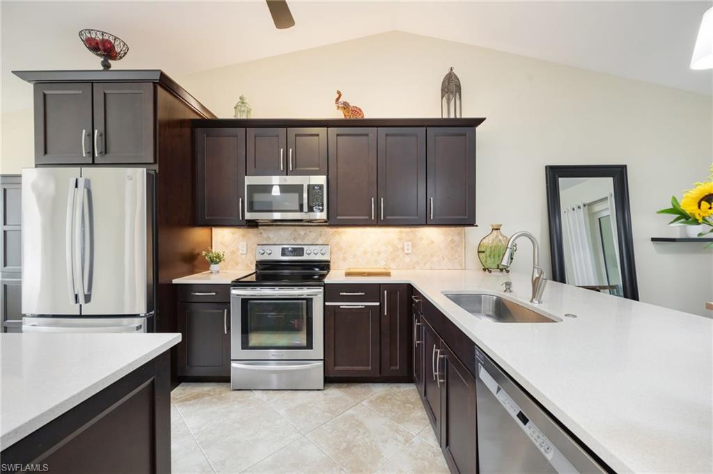 1324 Monarch Circle Naples, FL 34116 - Photo 5 of 23 a kitchen with stainless steel appliances granite countertop a sink stove and refrigerator