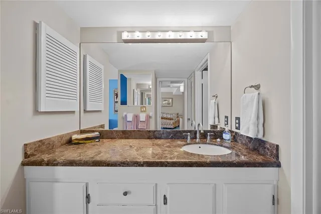 a bathroom with a granite countertop sink and a mirror