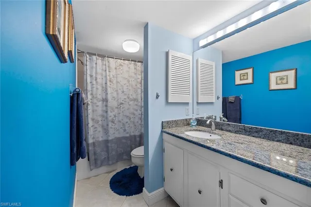 a bathroom with a granite countertop sink a toilet and shower