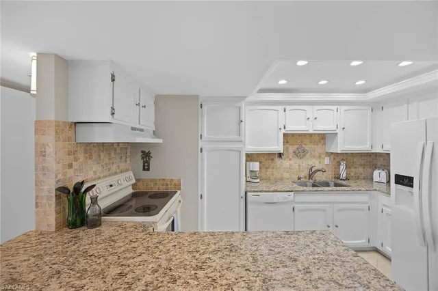 a kitchen with stainless steel appliances kitchen island granite countertop a sink refrigerator stove and white cabinets