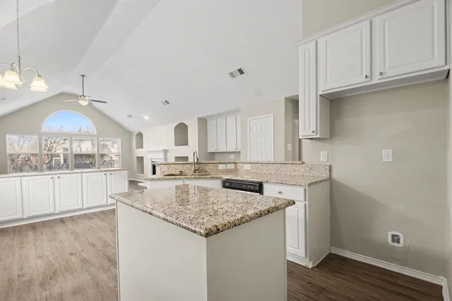 a kitchen with granite countertop a sink cabinets and wooden floor