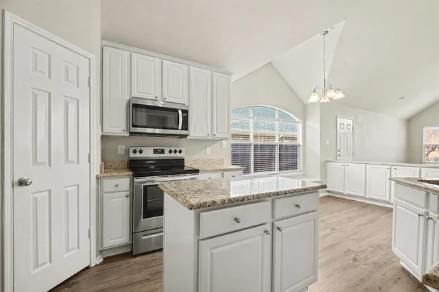 a kitchen with granite countertop a stove a sink and a microwave