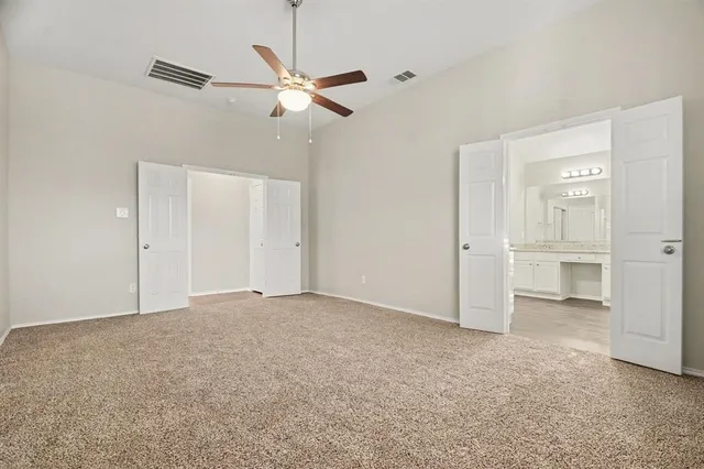 an empty room with closet and a ceiling fan