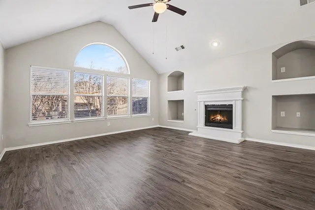 an empty room with windows fireplace and wooden floor