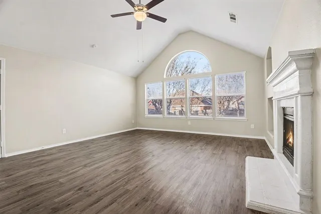 an empty room with wooden floor fan and windows