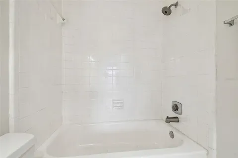 an empty room with wooden floor chandelier fan and windows