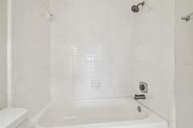 an empty room with wooden floor chandelier fan and windows