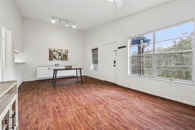 a view of an empty room with wooden floor and a window