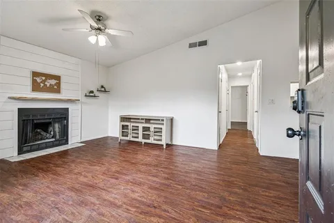 a view of an empty room with wooden floor a fireplace and a window