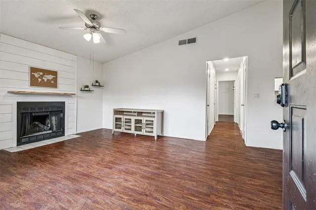 a view of an empty room with wooden floor a fireplace and a window