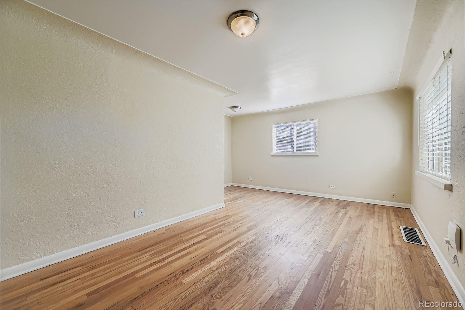3690 Magnolia Street Denver, CO 80207 - Photo 2 of 17 an empty room with wooden floor and windows