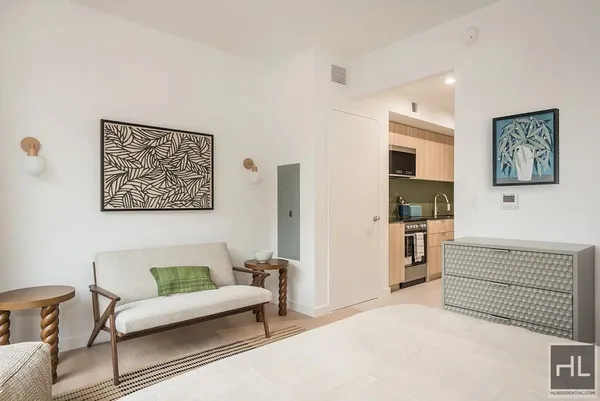a living room with furniture a refrigerator and kitchen view