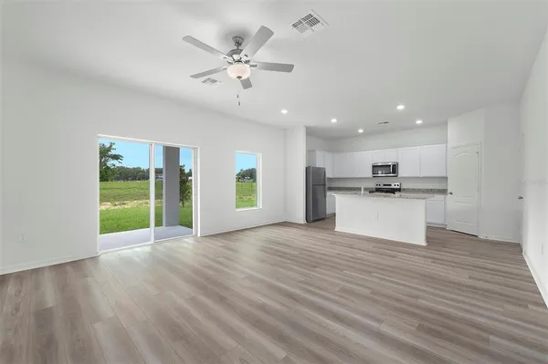 a view of an empty room with kitchen and window