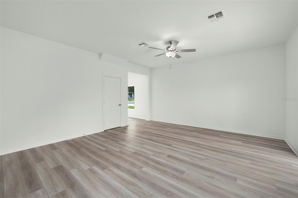 13291 Tula Loop Astatula, FL 34705 - Photo 5 of 22 a view of an empty room with wooden floor and a ceiling fan