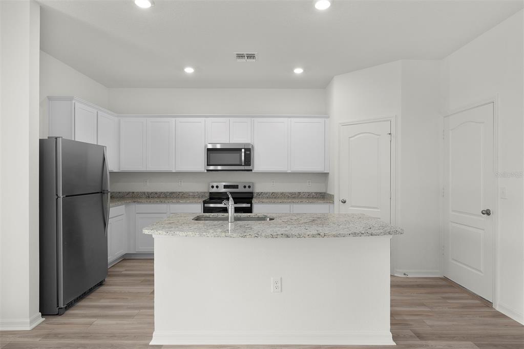 13291 Tula Loop Astatula, FL 34705 - Photo 7 of 22 a kitchen with stainless steel appliances granite countertop a refrigerator a stove and a sink