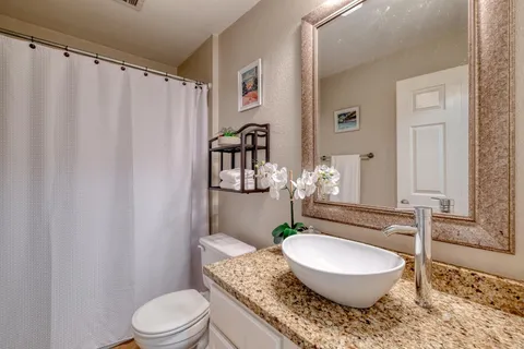 a bathroom with a granite countertop toilet a sink and a mirror