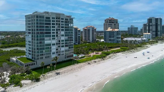 a front view of a building with a garden and trees