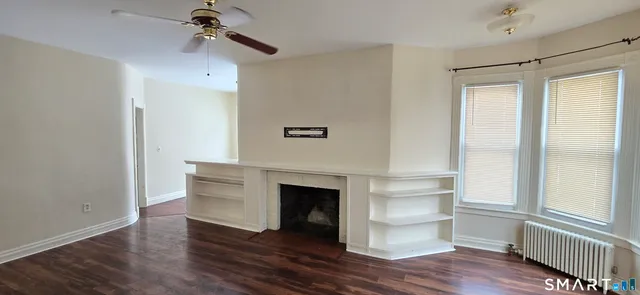 a view of a livingroom with wooden floor and a ceiling fan