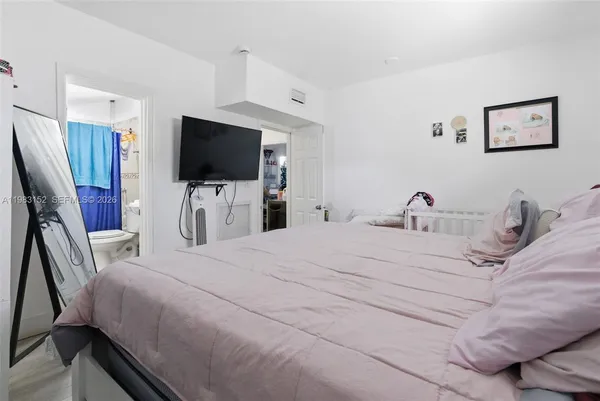a bedroom with a bed and a flat tv screen on wall
