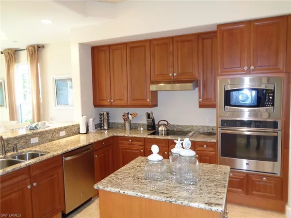 a kitchen with kitchen island granite countertop a sink stove and cabinets